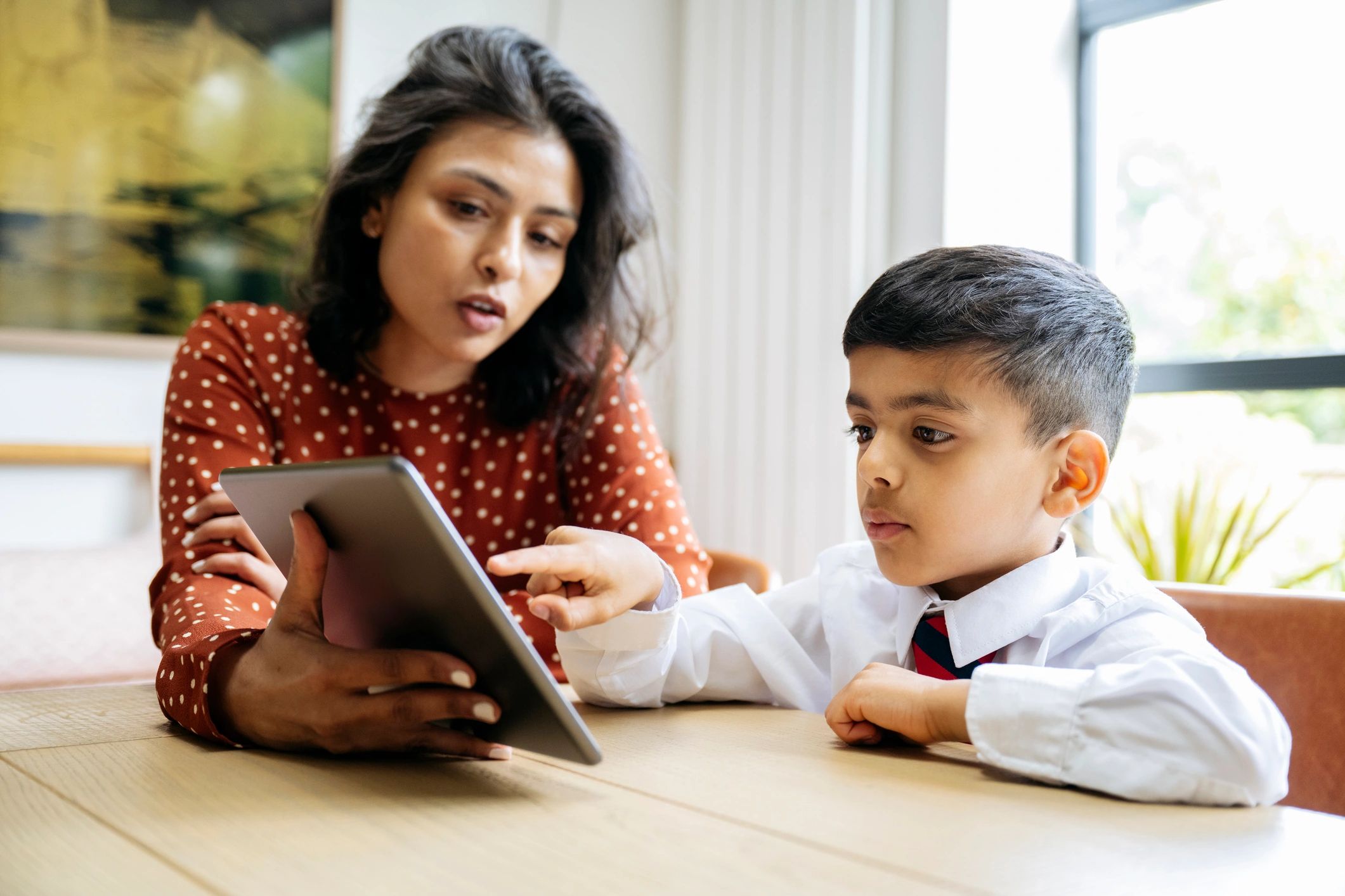 Adult supporting a young learner during a writing activity